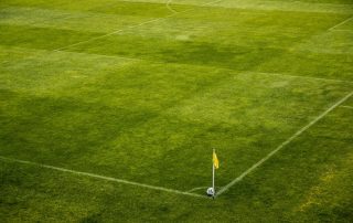 white and black soccer ball in the corner of a green football pitch