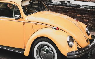 A yellow volkswagen Beatle parked in the street