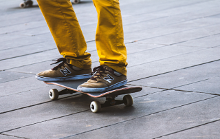 A man skateboarding wearing yellow trousers